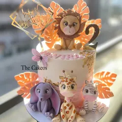 A beautiful jungle animal cake with a soft pink and orange color scheme. This design features a lion, elephant, giraffe, and zebra, all with sweet, friendly faces, perfect for a little girl's birthday.