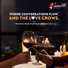 Where conversations flow, and the love grows. This image of two wine glasses against a romantic, softly lit background perfectly captures the essence of a perfect date night at Aerocity.