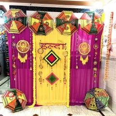 A detailed, straight-on shot of the Haldi backdrop, highlighting the 'Haldi' text in Hindi, dreamcatchers, and colorful umbrellas.