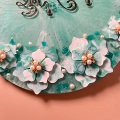 A close-up of the hand-sculpted 3D flowers on the sea-green pooja thali. Each flower is detailed with a pearl center.