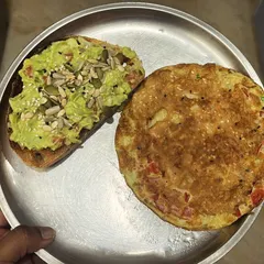 A client's delicious and satisfying meal of a vegetable cheela (savory pancake) served with a side of avocado toast topped with mixed seeds for extra crunch and nutrients.