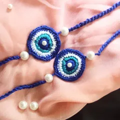A close-up of our evil eye rakhis, showing the detailed crochet work in shades of blue, white, and turquoise. These are a sustainable and reusable alternative to traditional rakhis.