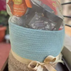 A beautiful two-toned jute basket filled with an assortment of goodies. Wrapped in a delicate net with a gold ribbon, this hamper is ready to be delivered as a wonderful surprise.