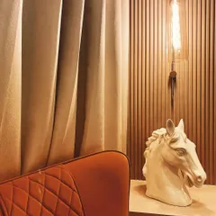 It's all about living in style. A simple corner is elevated with a bold, quilted armchair, a modern horse head sculpture, and an industrial-style pendant light, creating a chic and personal reading nook.