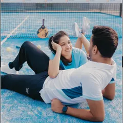 A playful, candid moment of laughter and connection, showing the couple relaxing on the court between games.