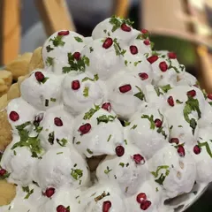 A mountain of soft Dahi Vadas, soaked in creamy yogurt and garnished with fresh coriander and pomegranate seeds. A refreshing and classic chaat option.