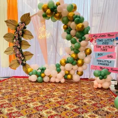 This gender-neutral baby shower decor features a half-ring frame decorated with green, white, and gold balloons. An "Oh Baby" neon sign and fun gender-reveal signs on the side add a playful yet stylish element to the party.