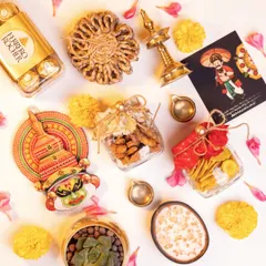 A flat lay of the 'Eternal Onam Luxe - Ponnonam' hamper contents. You can see the mix of traditional snacks in jars, a brass lamp, a Kathakali face decor, a succulent plant, and Ferrero Rocher chocolates, all ready to be assembled.