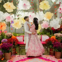 A romantic shot of the couple in the midst of the colorful Mehendi garden. The backdrop of giant paper flowers and lush blooms creates a dreamy, fairytale-like setting.