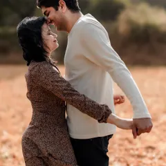 Holding hands and sharing a look of love. The warm, earthy tones of this outdoor setting in Bangalore create a perfect backdrop for a romantic couple shoot.