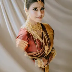 This portrait of a traditional Bengali bride is a study in elegance. The soft, diffused light and the sheer curtain create a dreamy effect, perfectly complementing her golden jewelry and red saree.
