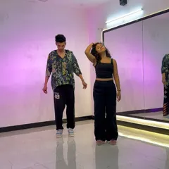 A still from a duet choreography session. The purple lighting and mirror reflection capture the cool, modern vibe of this dance studio.