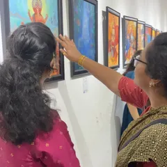 Visitors admiring a student's artwork at the exhibition, showing the engagement our events create.