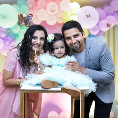 A smiling family poses with their one-year-old daughter at her pastel-themed birthday party. Our approach is friendly and relaxed to help everyone feel comfortable in front of the camera.