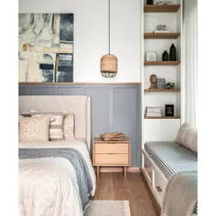 Simplicity and elegance define this master bedroom. I used MDF wainscoting on half of the bed wall, painted in a soothing grey, with the other half in pure white. This creates a calm backdrop for the light beige upholstered bed and oak side tables.