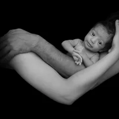 This black and white portrait captures a newborn held securely in the loving arms of their parents. I focus on creating these powerful, emotional images that highlight the family's bond.