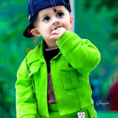 A stylish little boy in a bright green jacket, lost in thought. This baby portrait showcases how I use vibrant colors and natural light to create memorable and cute baby photos.