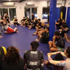 Students watching intently as a complex sweep is demonstrated during the seminar. The focus here is on absorbing the concepts of leverage and positioning from a top-level practitioner.