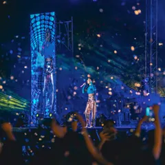 A wide shot of Dhvani Bhanushali's performance. The combination of a custom blue top and metallic Ganni pants creates a vibrant, eye-catching look that fills the entire stage.