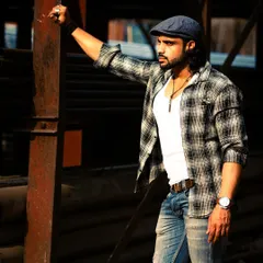 A different look in the same industrial setting. The plaid shirt and cap give off a more casual, rustic vibe against the metal structures.