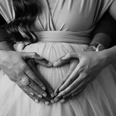 A close-up on the heart of the matter. This artistic shot focuses on the couple's hands forming a heart on the baby bump, a simple and beautiful symbol of their love.