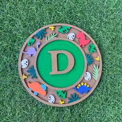 Roar! This dinosaur-themed monogram kit is perfect for any dino lover. The "D" initial is set against a backdrop of prehistoric leaves, eggs, and colorful dinosaurs that you get to paint and arrange yourself.