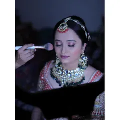 This image, framed by my ring light, shows the process of applying blush to add a warm, healthy glow to the bride's cheeks for her reception look.