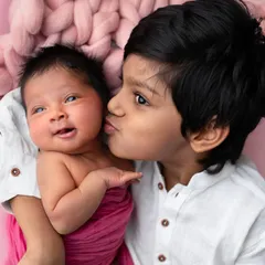 A gentle kiss from a big brother to his newborn sister. These unscripted, tender moments are what make sibling portraits so deeply meaningful.