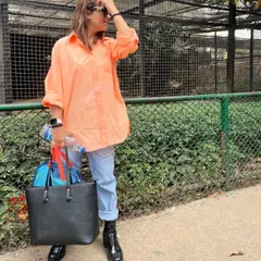 This shows the versatility of one outfit. By swapping the heels for chunky black boots and adding a large tote bag, the same peach shirt and jeans are transformed into a practical and stylish look for a day out.
