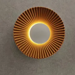 A close-up of the pleated sunburst wall sconce, highlighting its detailed texture and warm, indirect glow.