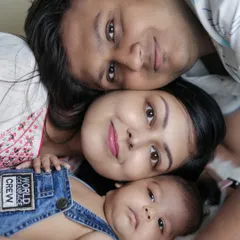 A lovely family portrait from above, with the parents and their newborn lying close together, looking up at the camera. A unique and intimate perspective.