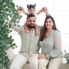 A happy family portrait using a simple window light setup with touches of greenery. The coordinated neutral outfits and bright lighting create a fresh, modern, and authentic family photo.