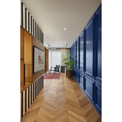 The entryway of the "Blue is the Warmest Colour" apartment. A striking Parisian-style paneled wall in a warm blue hue conceals doors and sets a sophisticated, intriguing tone for the entire home.