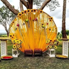For a unique Haldi or Mehendi, I design vibrant outdoor setups. This circular backdrop with bright yellow drapes and sunflowers creates a cheerful and picturesque spot for your ceremony.