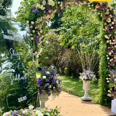 The entrance to a beautiful garden engagement. A grand floral arch filled with lilac, lavender, and white blooms welcomes guests into the serene, nature-inspired setting.