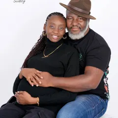 A happy and relaxed couple portrait in a high-key studio setting. Their casual black outfits and joyful interaction create a natural and heartwarming image.