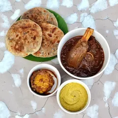 Our signature Champaran Mutton, deconstructed for delivery. You get the tender, fall-off-the-bone meat in its rich, rustic gravy, paired with flaky Sattu Parantha, roasted garlic, and a sharp mustard chutney. It’s a complete, hearty meal, packed to preserve every element.