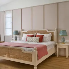 This bedroom from 'House of Kismish' is a French-inspired affair with a delicate pastel hue. The custom-made bed with a cane headboard and footboard is set against a paneled wall, creating a soft and alluring ambiance.
