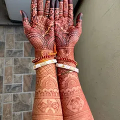 The gorgeous, deep red stain of a bridal mehendi, adorned with traditional Bengali wedding bangles (shakha pola).
