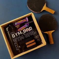 For the brother who lives at the gym, I designed this "Gym Bro" hamper. It's packed with practical fitness essentials like a protein shaker, grip gear, protein bars, and even some skincare, all presented in a custom wooden box.