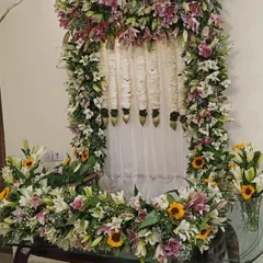 A full view of a Ganpati mandap decorated with an abundance of fresh lilies, sunflowers, and hanging floral strings.