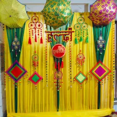 A full view of the 'Dulheraja' Haldi backdrop, featuring bright yellow drapes, decorative umbrellas, and colourful thread-work hangings.