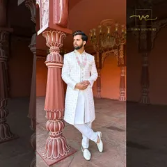 An elegant white sherwani with intricate self-embroidery, paired with a matching necklace. A regal choice for the main wedding ceremony.