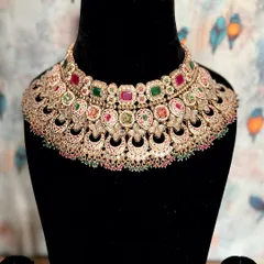 This beige Meenakari Kundan necklace is a work of art. The ruby and emerald stones set against the subtle enamel work create a look of enchanting, regal elegance.