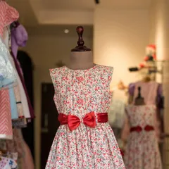 A beautiful floral print dress with a simple silhouette. I added a bold red satin bow to give this classic design a striking and memorable accent.