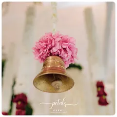 A single brass temple bell, adorned with a puff of pink nerium flowers, hanging from a string of tuberose. It's these small, beautiful details that create a truly special atmosphere.