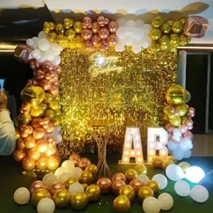 A beautiful backdrop for any birthday, featuring a gold sequin wall and a balloon arch in rose gold, gold, and white. The light-up initials add a personal touch.
