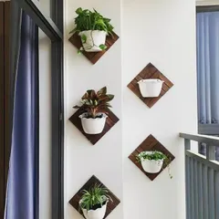A simple and charming way to decorate a balcony wall. We mounted these small white pots on diamond-shaped wooden backings, creating an affordable and stylish vertical display for a variety of small indoor plants.