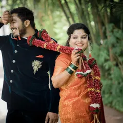 A playful and happy moment after the ceremony, with the bride draping the wedding garland over the groom's shoulder.