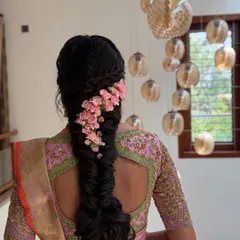 For a softer, more romantic bridal style, I designed this intricate fishtail braid adorned with a cascade of delicate pink flowers. This look is perfect for pre-wedding events like an engagement or sangeet, blending traditional braiding techniques with a modern floral touch.